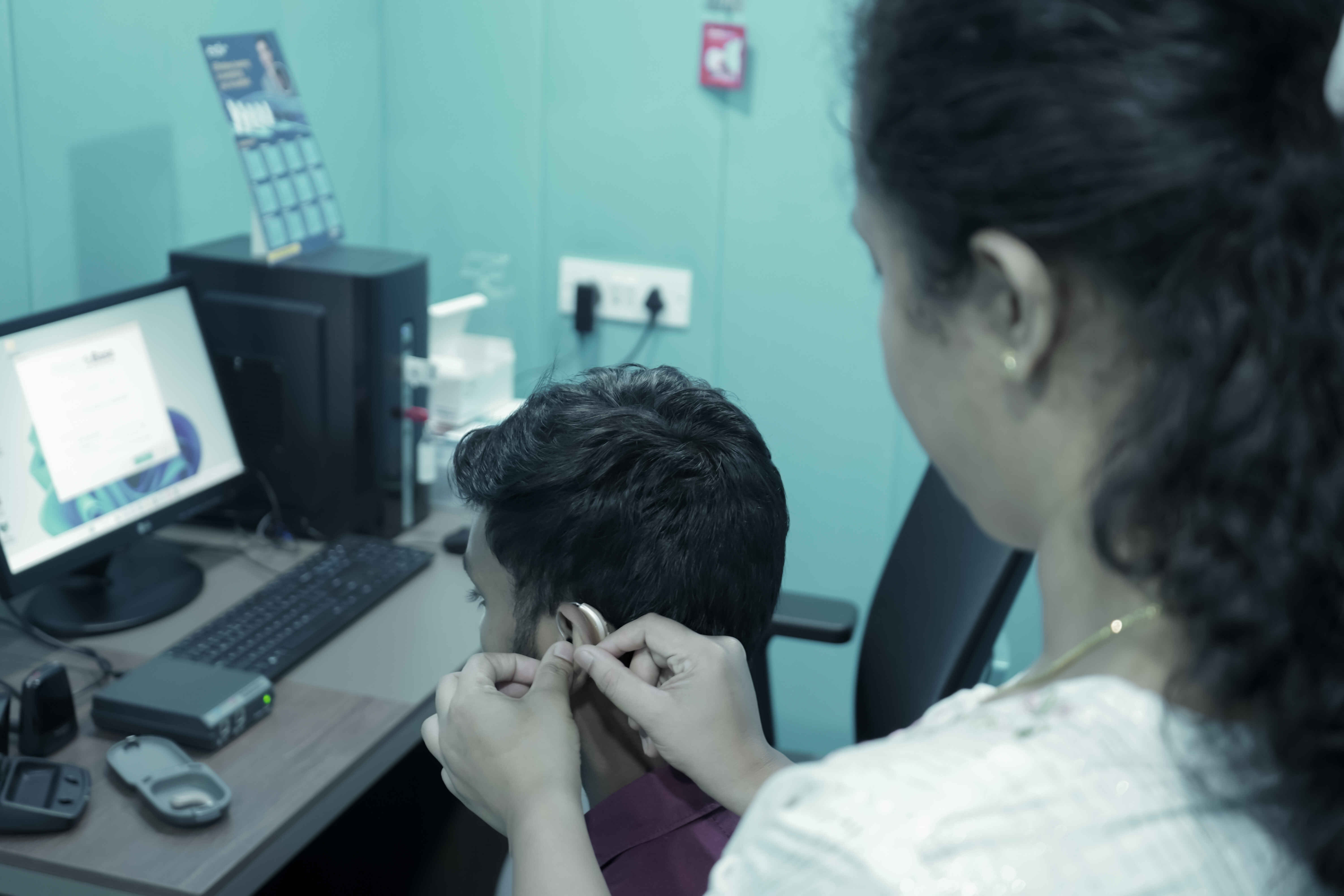 A hearing aid being placed in a patient's ear